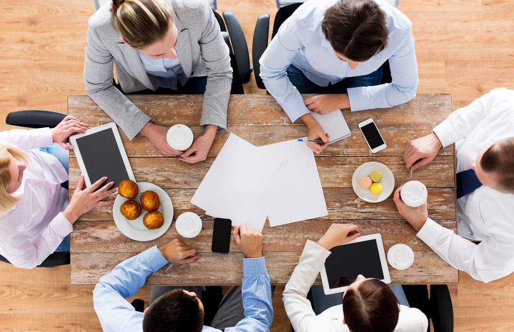 business team around a table having coffee and plans